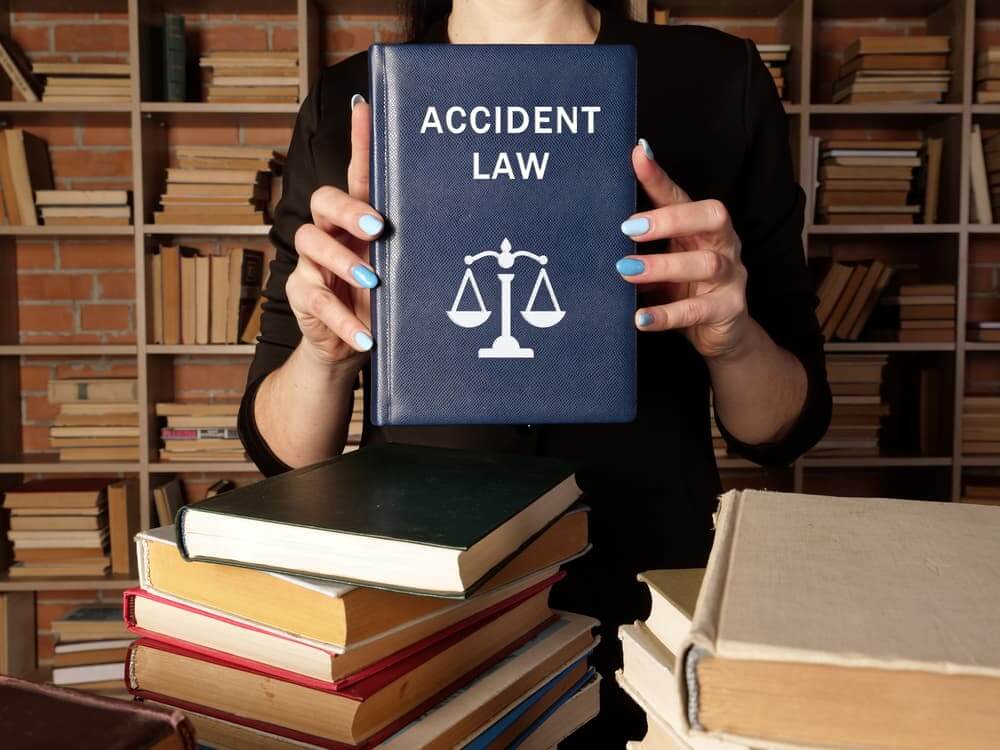 A jurist is holding a book on accident law. Car accident law encompasses the legal principles that establish liability for personal injuries resulting from automobile collisions.