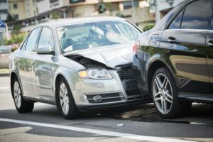 Automobile collision on the street, resulting in damaged vehicles.