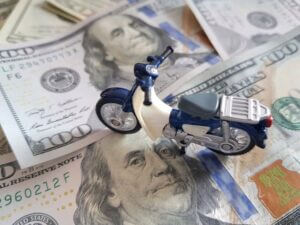 Toy motorcycle on money pile, symbolizing value in motorcycle accident case