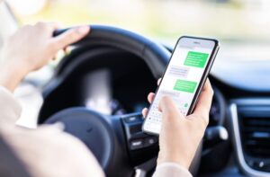 A woman texting on her phone while behind the wheel of a car