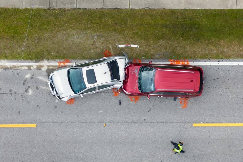 Aerial view of a car damaged from a collision with another vehicle on the road.