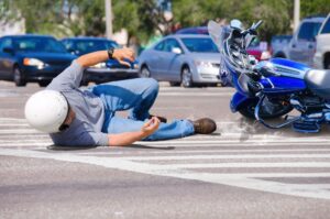 An injured man next to a fallen motorcycle