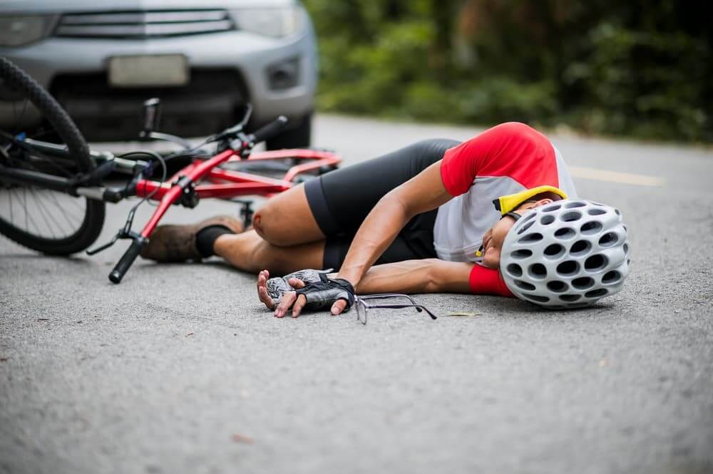 An Asian mountain biker was injured in a collision with a car on the road. The concept emphasizes reducing accidents involving cyclists and vehicles.