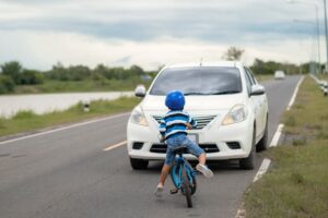 An Asian boy was injured when his bicycle collided with a car on the road. The boy was hit by the car during the accident.