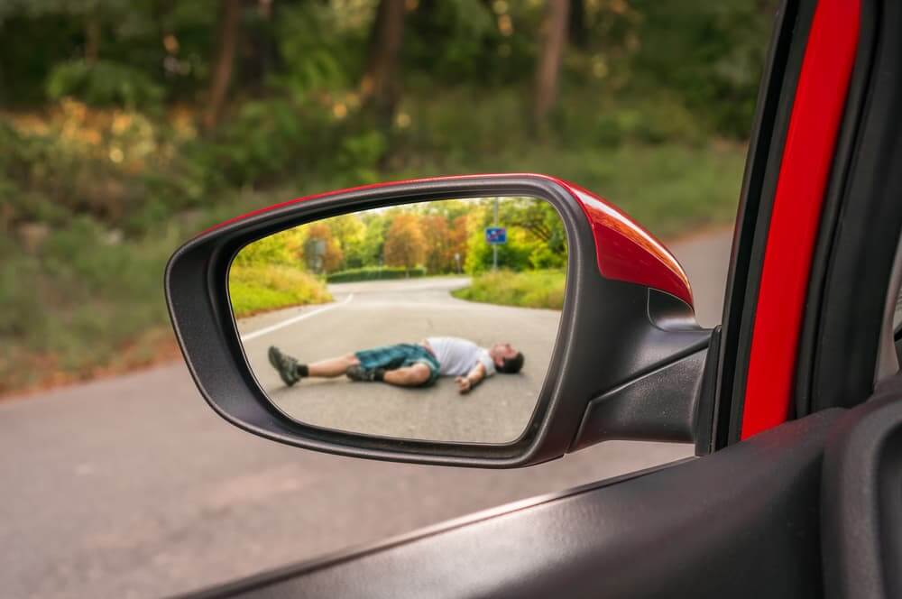 Reflection in rearview mirror showing a man struck by a car – illustrating a car accident scenario.