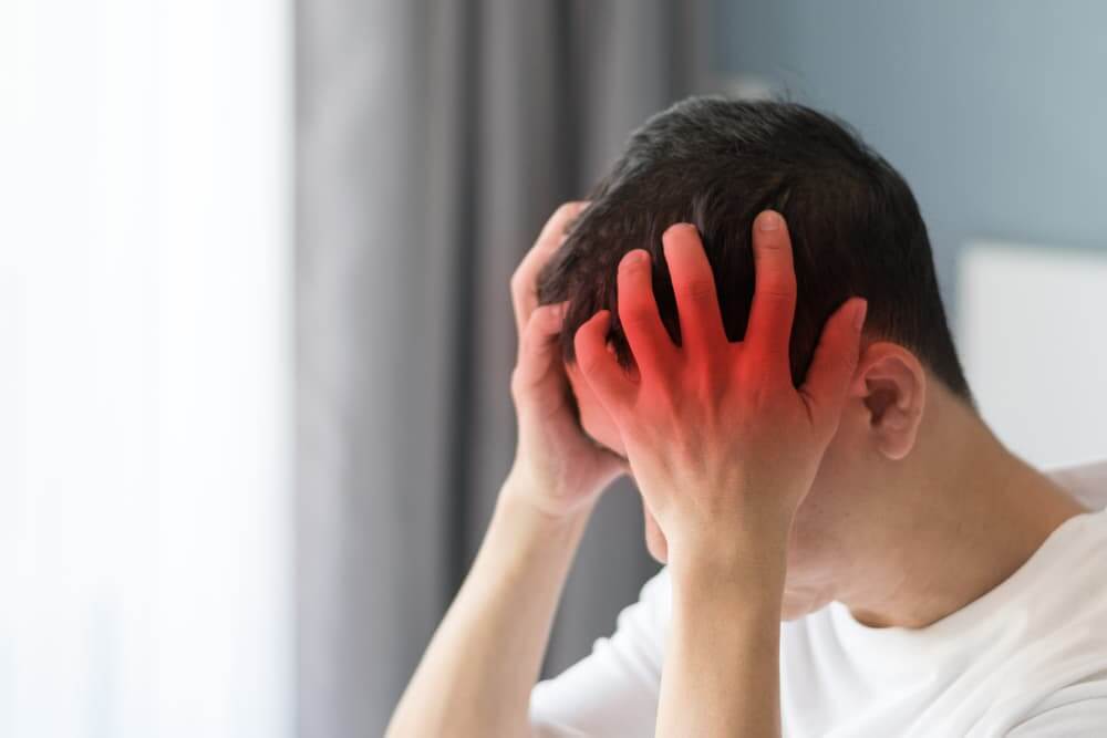 Chronic brain diseases cause severe headaches and migraines. An adult male appears exhausted, stressed, and depressed, struggling with mental health issues.