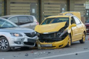 The image of two cars that have crashed, with one being a yellow taxi and the other a private car. The scene depicts the aftermath of the accident with visible damage to both vehicles.