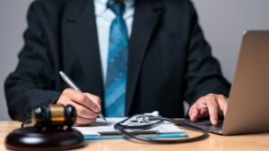 Image of a lawyer in a professional office setting, reviewing medical documents and legal files, with a stethoscope and scales of justice on the desk to symbolize the intersection of law and medicine. The lawyer looks focused and determined, highlighting their expertise in navigating complex personal injury cases. The background suggests a professional and supportive environment, emphasizing the importance of legal guidance in achieving fair resolutions in medically intricate scenarios.