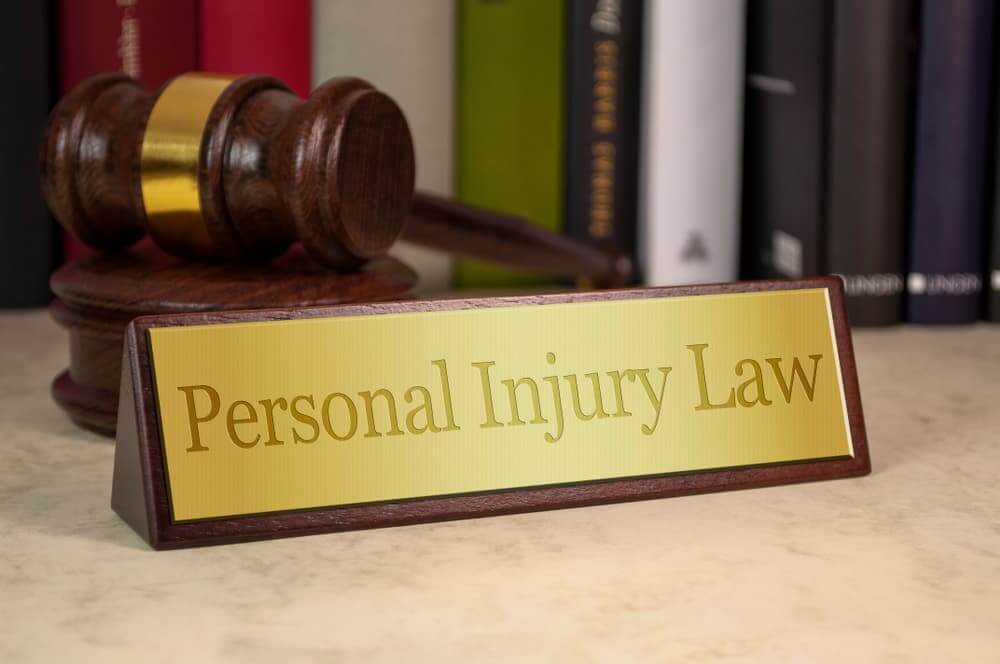 Golden sign on a table with law books and gavel with personal injury law