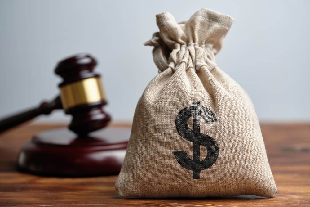A bag full of dollar and attorney hammer in background