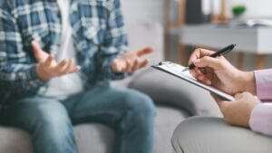 Therapist using clipboard while listening to patient, emphasizing importance of seeking medical help after car accident. 