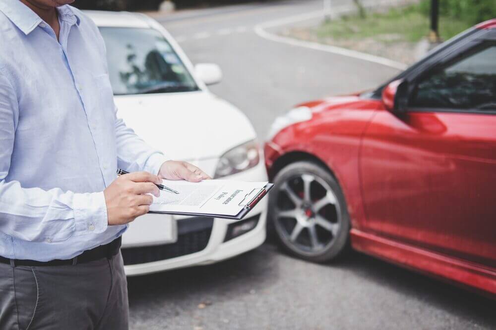 insurance agent fills out accident report form to process claim after crash with uninsured at-fault driver.