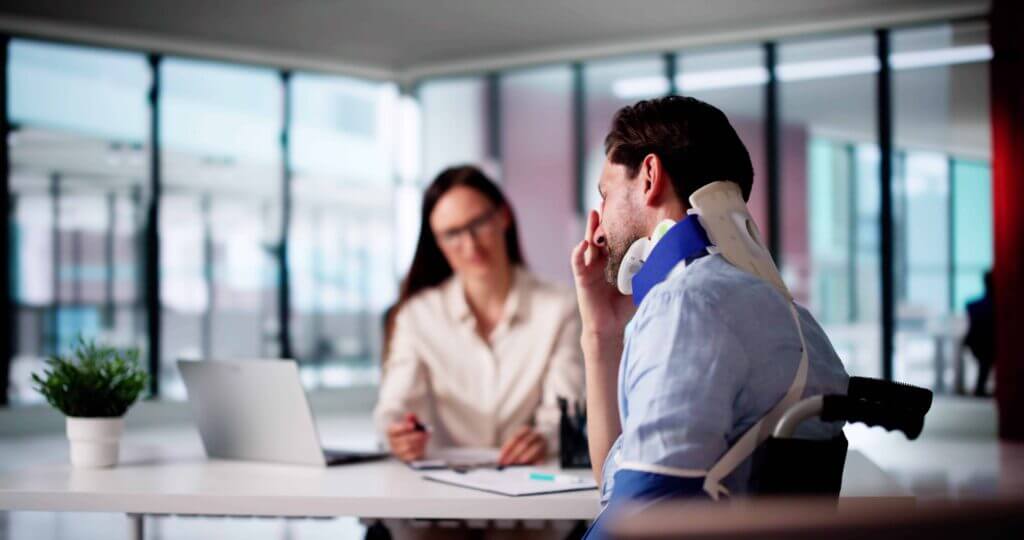 Injured man with neck brace consulting personal injury lawyer about accident claim in office.