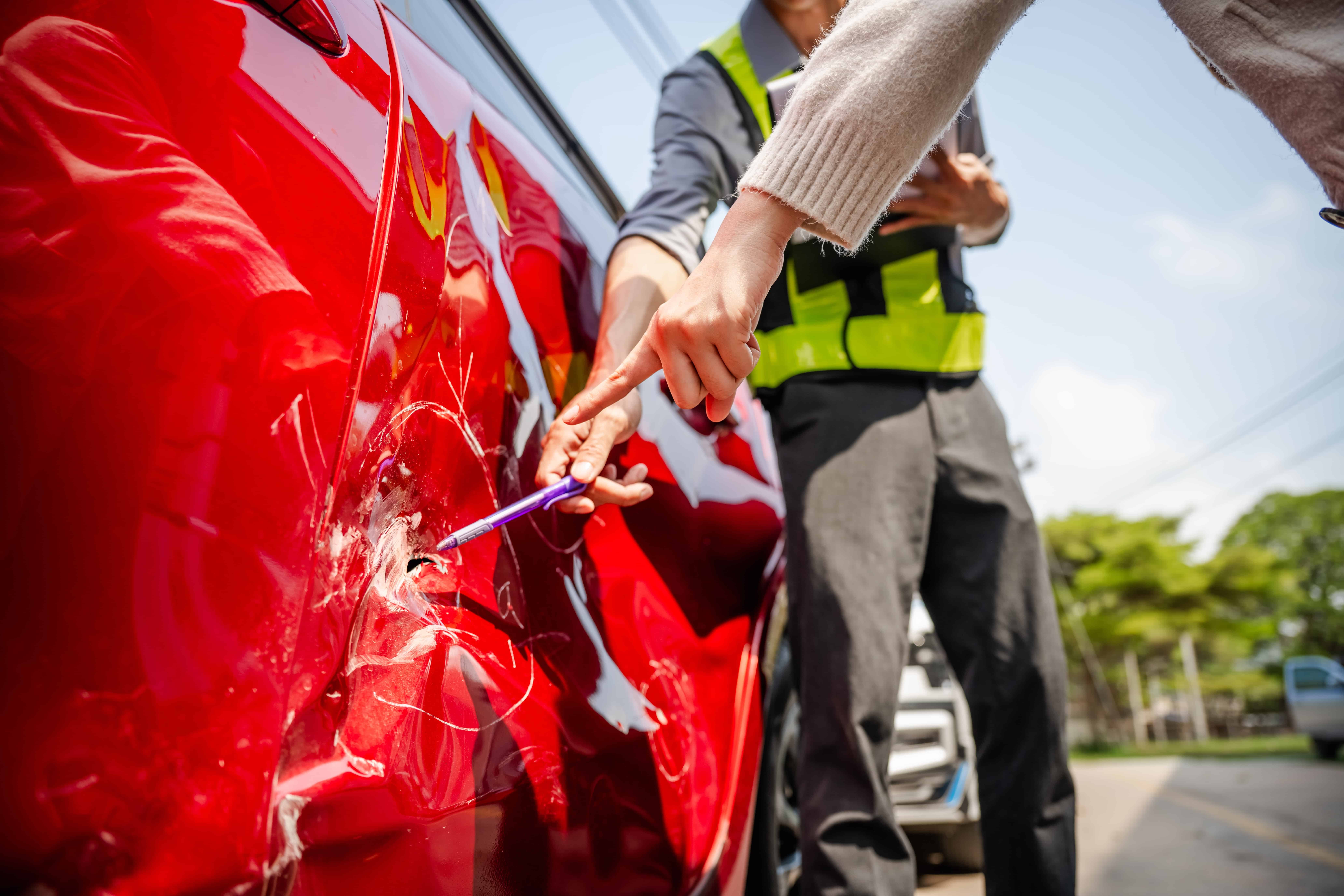 Insurance agent inspecting and pointing at car door damage after a vehicle accident. Insurance agent inspecting and pointing at car door damage after a vehicle accident.