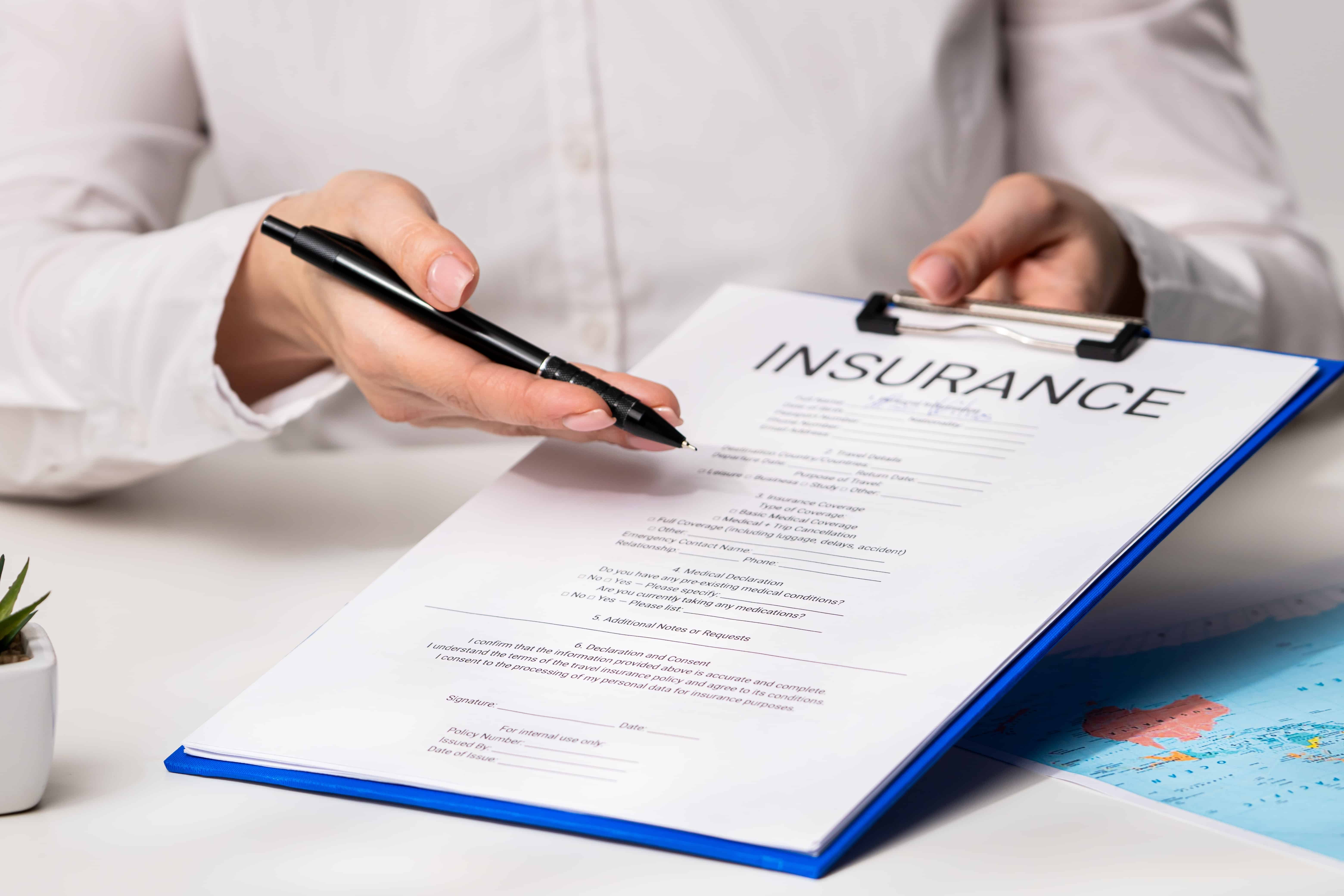 Person holding and reviewing an insurance policy document on a clipboard.